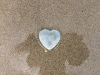Heart stone on shadow and sand beach for concept valentine day.