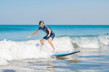 Young man, beginner Surfer learns to surf on a sea foam on the Bali island
