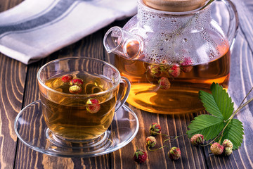 In a mug and teapot red berry tea from a forest strawberry on a wooden table top.Healthy drink from strawberries.