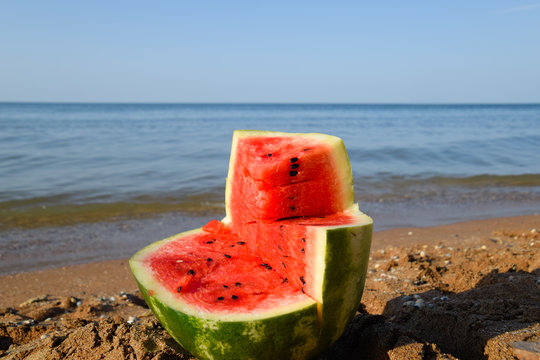 The cut watermelon lies on the seashore. Watermelon in the sea