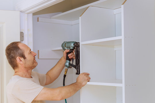 Carpenter Worker Joint Air Gun Hanging The Shelf Some Wall-mounted Brackets.