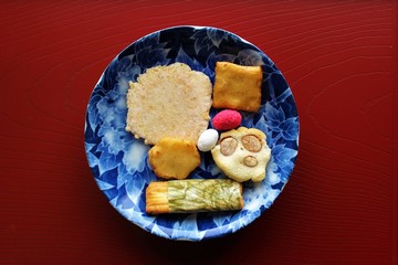Rice crackers in a blue dish on a red board