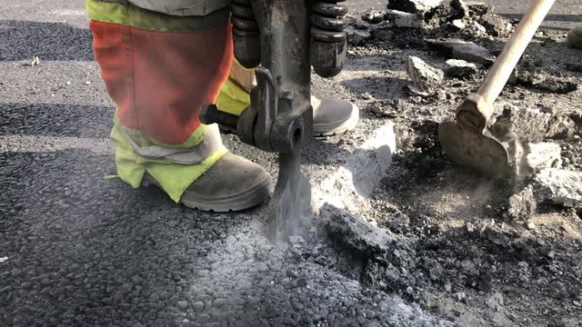 Hackhammer machine destroying asphalt road