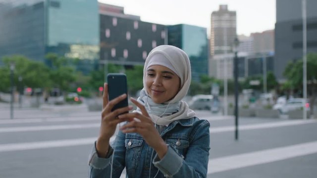 portrait of young modern muslim woman taking photo of city building using smartphone camera technology enjoying urban evening sightseeing travel