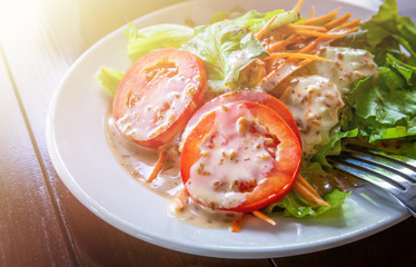 Fresh salad with sesame dressing without meat on white ceramic dish.