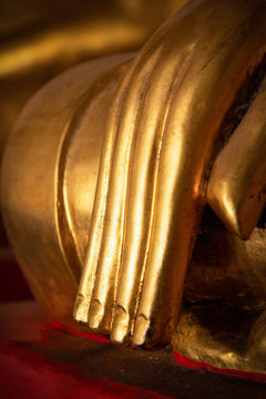Vertical scene of close focus on fingers and hand of golden Buddha image as meditation posture represents highly concentration.