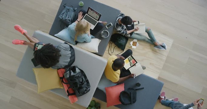 diverse young group of college students study together using mobile technology working on project exam in modern recreational workspace top view