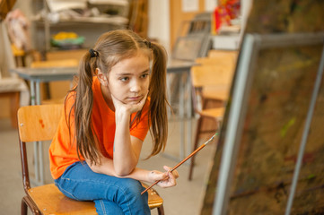 pensive girl looks at the picture in the school