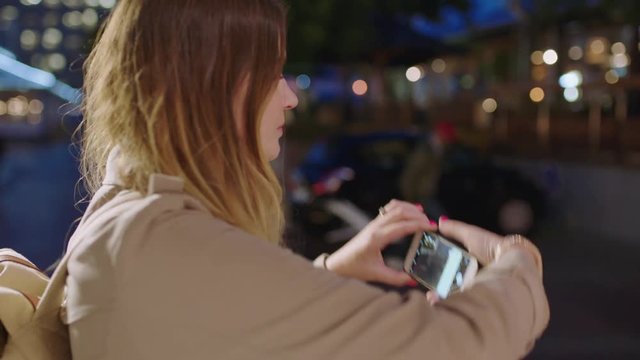 close up portrait of pretty blonde woman tourist taking photo with smartphone enjoying calm urban evening