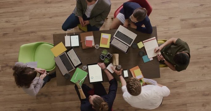 young diverse business people in meeting working together brainstorming creative solutions for startup marketing company in modern boardroom above view