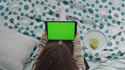 top view young woman using tablet pc video chat waving hand enjoying communication sitting relaxed on bed female watching green screen