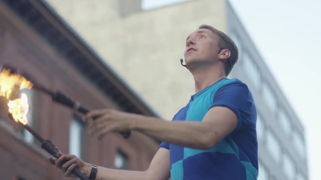 Low angle slow motion juggler with fire torches