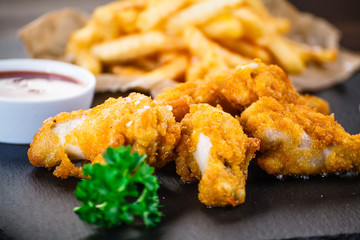 Chicken nuggets with french fries on black stone plate