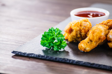 Chicken nuggets with french fries on black stone plate