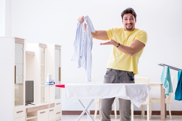 Handsome man husband doing clothing ironing at home