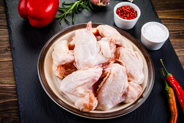 Raw chicken wings on black stone on wooden background