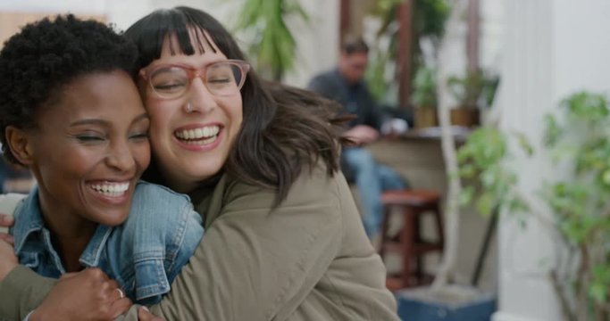 portrait of young woman surprise hugging friend diverse girlfriends embracing laughing enjoying friendship hang out together in urban background
