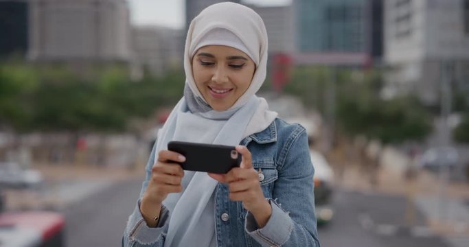 portrait young happy muslim woman using smartphone taking photos in city enjoying sharing vacation travel experience wearing hijab headscarf modern lifestyle urban background