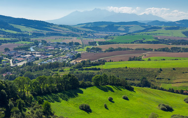 rural area around the town. grassy hill and agricultural fields. High tatra mountain ridge in the distance. view from the top of a castle tower