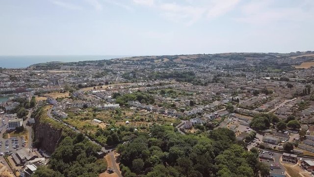 Aerial view of town and coastline in Brixham, England. Sky view of homes, hotels, and resorts in England.