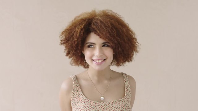 portrait of young shy mixed race woman with afro smiling bashful student 