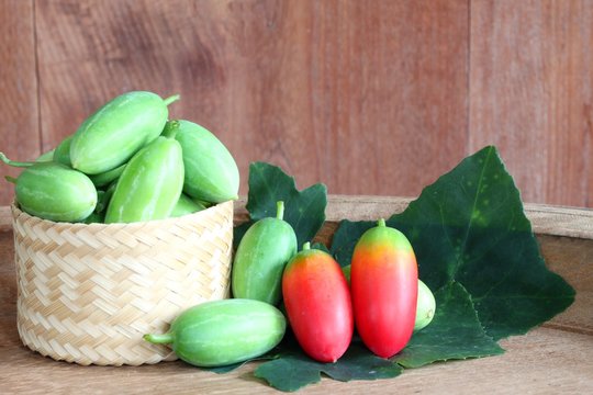 Lvy Gourd or cocconia grandis fruit with leaves on wooden background.