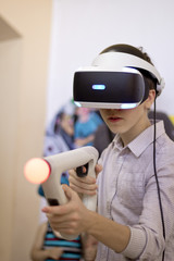 Boy using VR glasses and headset plays computer games. Virtual game.