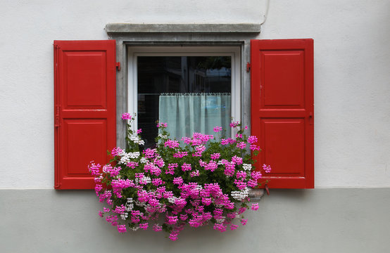 Finestra decorata con geranei rosa e bianchi nel centro di Sottoguda