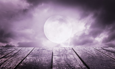 Halloween background. Spooky sky with full moon and wooden table