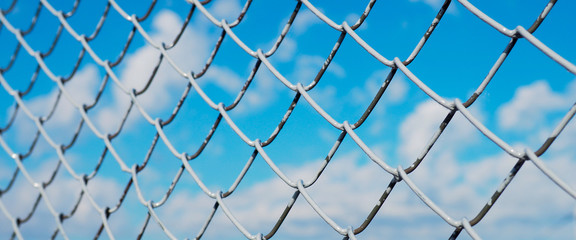 Fototapeta premium banner wor website, A fence made of wire mesh, netting covered with white on the background of blue sky and sunshine