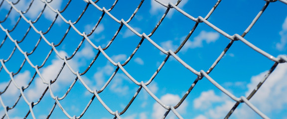 Fototapeta premium banner wor website, A fence made of wire mesh, netting covered with white on the background of blue sky and sunshine