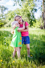 little girls hugging each other outdoors in summer