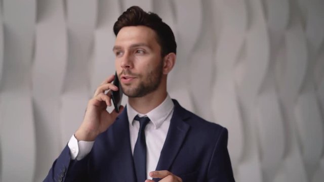 Berded young businessman walking and talking on the phone