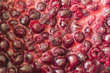 Cooking cherry jam.Cooked dark red cherries and red sugar syrup with foam.Interesting background. Site about fruits, berries,food,cuisine and cooking.