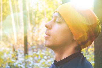 Young man with closed eyes close up in forest. Toned photo