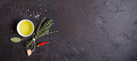Olive oil and bouquet of thyme on a black stone background