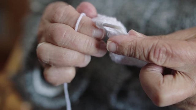 close up of elderly woman hands knitting needles