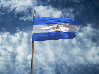 Nicaragua flag Silk waving flag of Nicaragua made transparent fabric with wooden flagpole gold spear on background sunny blue sky white smoke clouds real retro photo Countries of world 3d illustration