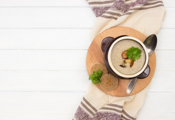 Fototapeta na wymiar Mushroom soup in pot and toasts on wooden board