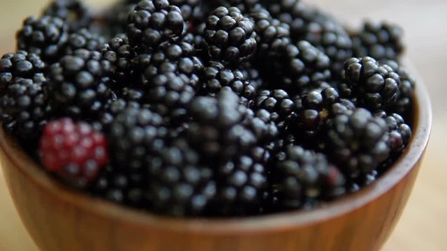 blackberries in bowl rotate on wooden table