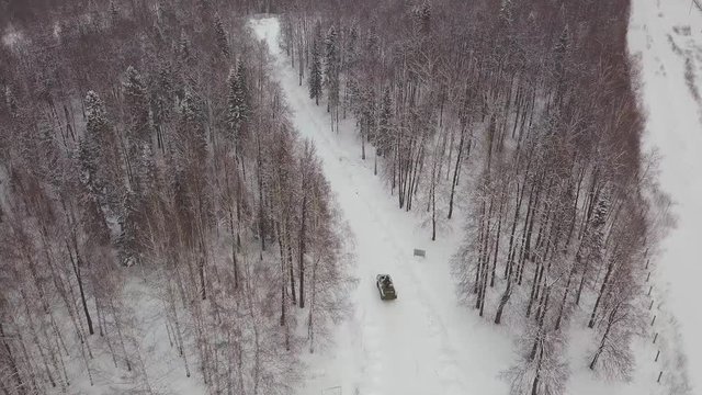 Aerial view of tank driving through the winter forest. Battle tank in the forest. Tank under the snow