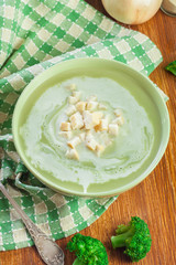 Broccoli cream soup in green bowl served with croutons