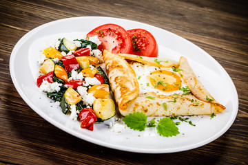 Crepes with eggs on wooden background