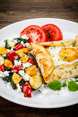 Crepes with eggs on wooden background