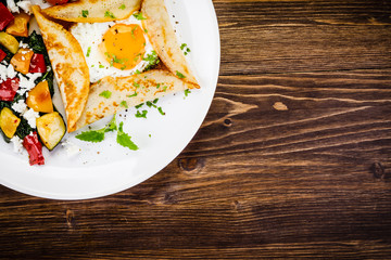 Crepes with eggs on wooden background