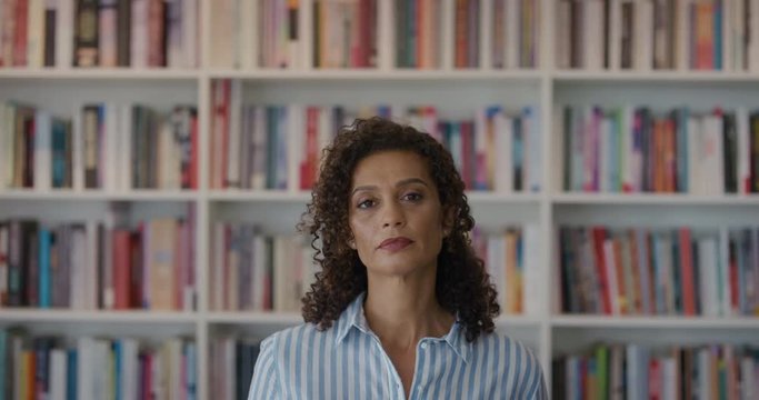 portrait mature mixed race business woman looking confident successful female entrepreneur in bookshelf background slow motion