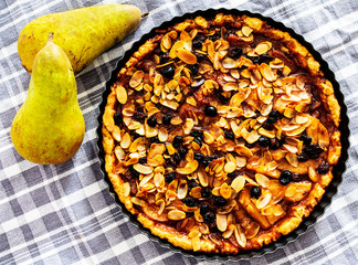 top view of rustic pear tart with raisins and sliced almonds in baking pan