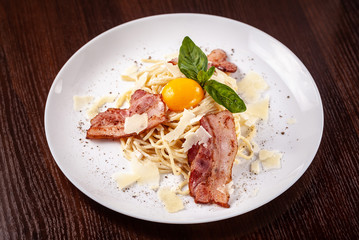 Italian pasta spaghetti carbonara, with fried bacon, parmesan cheese and egg yolk. It is on the table in the restaurant. Copy space, selective focus