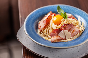 Italian pasta spaghetti carbonara, with fried bacon, parmesan cheese and egg yolk. It is on the table in the restaurant. Copy space, selective focus