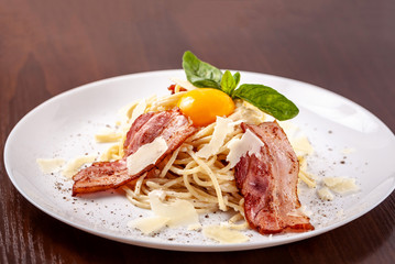 Italian pasta spaghetti carbonara, with fried bacon, parmesan cheese and egg yolk. It is on the table in the restaurant. Copy space, selective focus